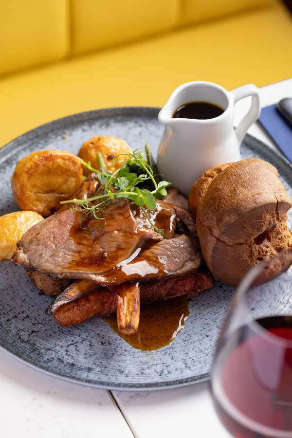 A Sunday roast with Yorkshire puddings and gravy by a yellow booth