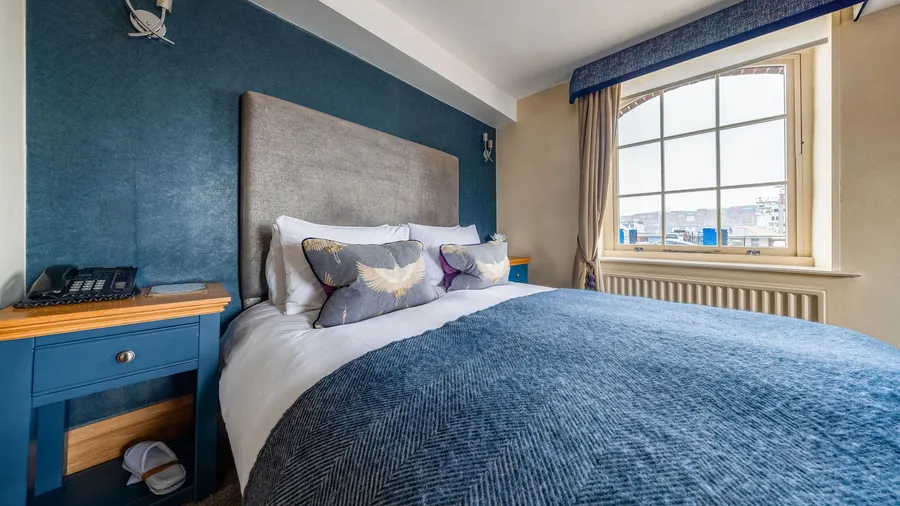 One of the bedrooms at Ennio's: a navy wall, a blue throw and a window over the water