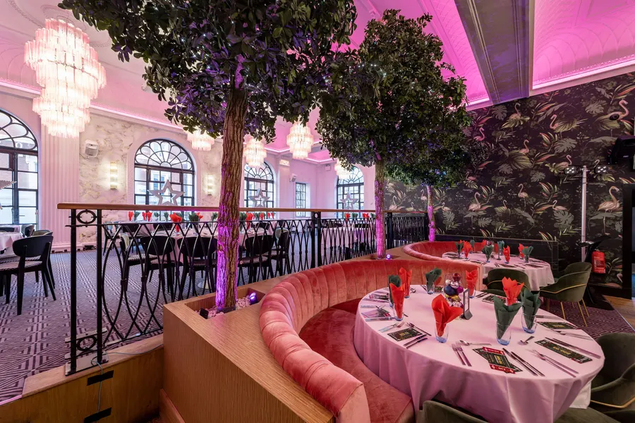 The Grand's dining room laid for Christmas, pink light across the ceiling