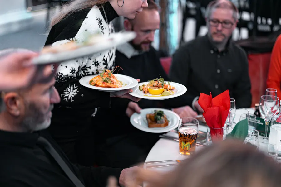 Plates of food carried through a full room at The Grand's Christmas party