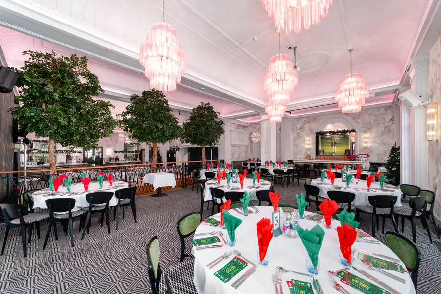 The Grand's ballroom laid with round tables for a Christmas party under the chandeliers