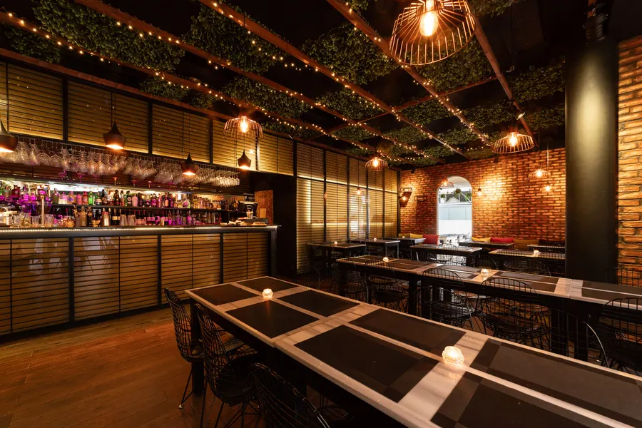 The dining room at Padharo in the evening, tables laid and the bar lit behind