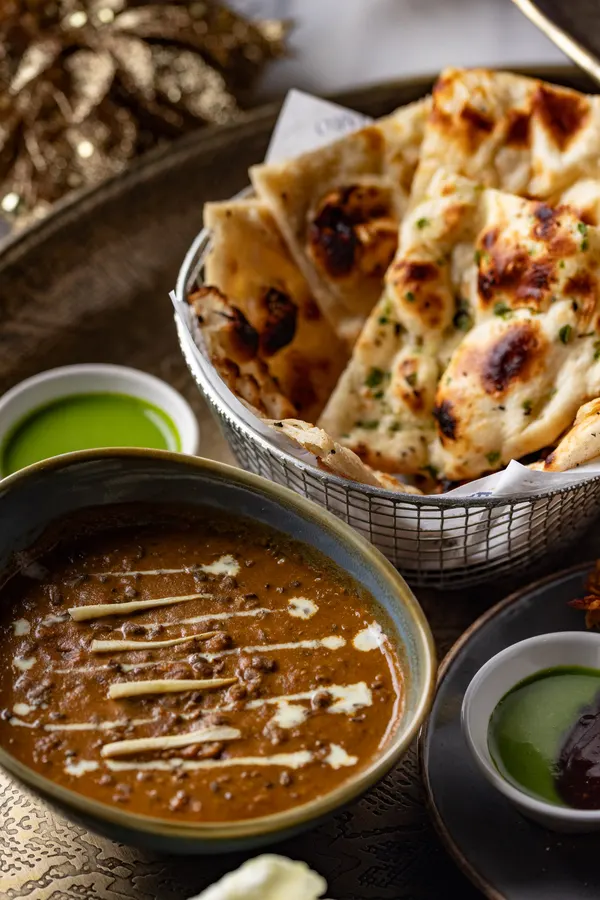 Garlic naan stacked beside a bowl of dal and green chutney